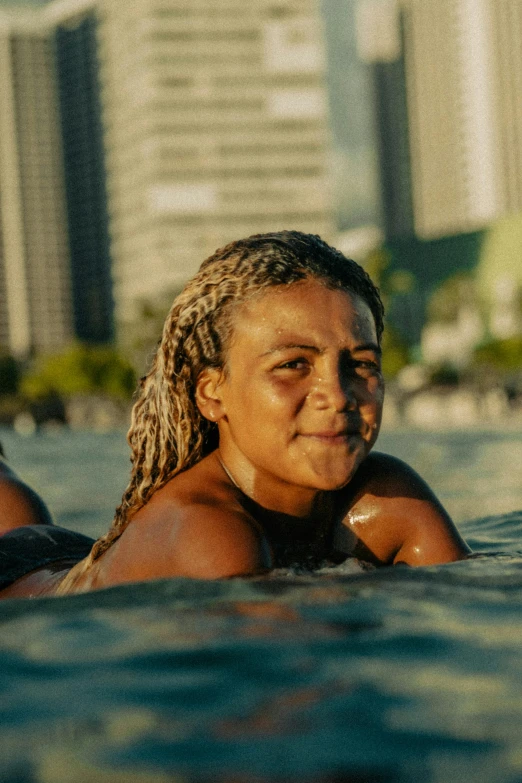 a woman is swimming in the ocean with buildings in the background