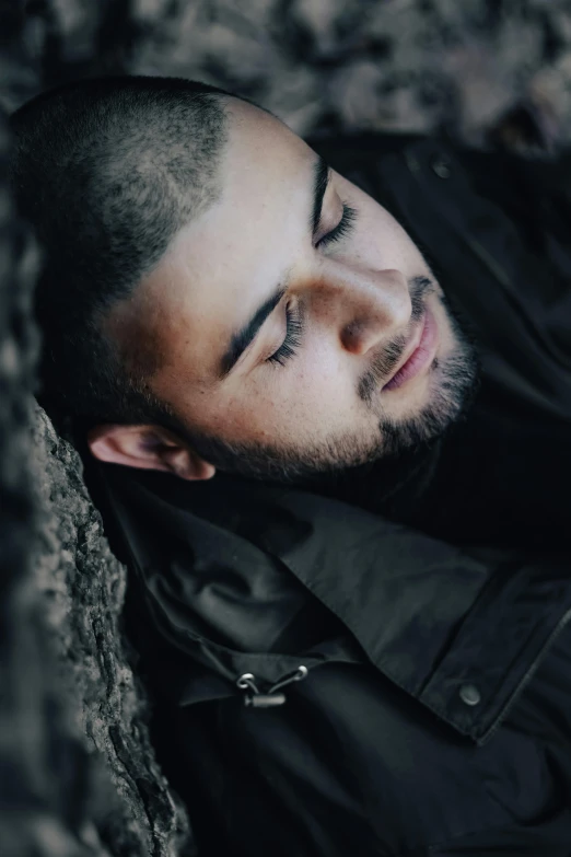 a man sleeping against a stone wall