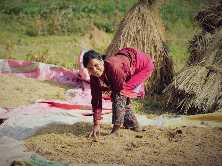 the woman smiles as she crouches by the pile of brown sand