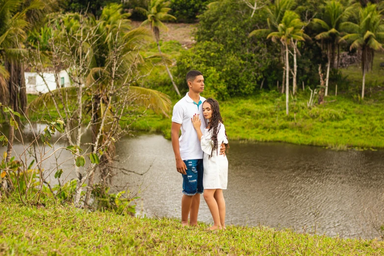 a couple standing next to a lake with palm trees