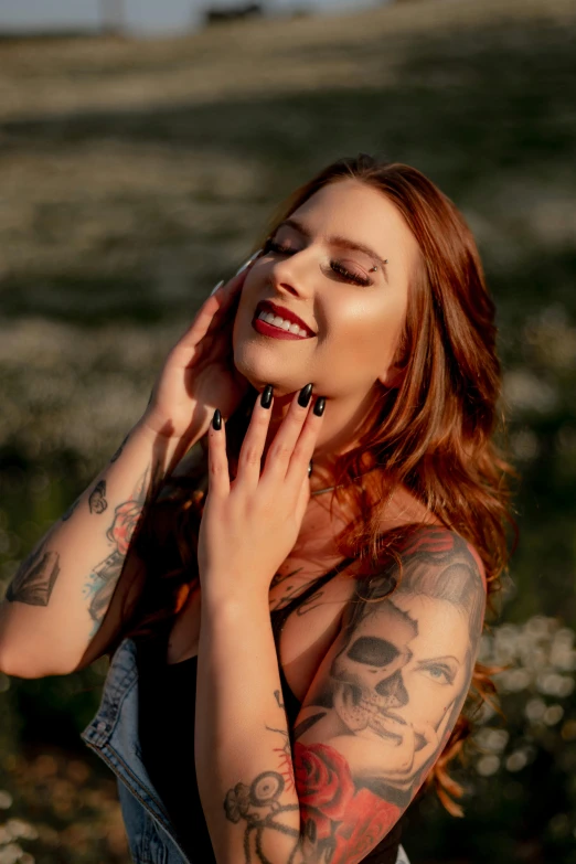 a young woman with tattooed arms holds her hands to her ear