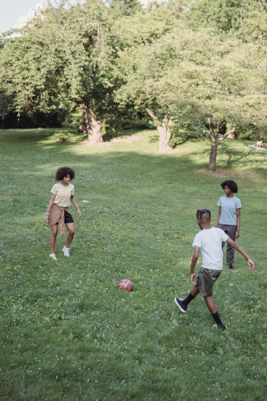 two girls and a boy playing soccer in the grass