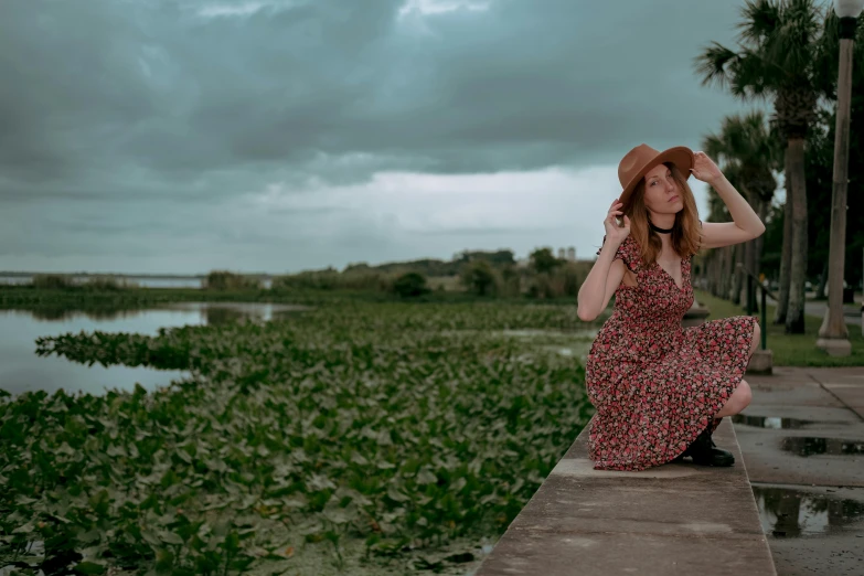 a woman in a flowered dress sitting on top of a stone wall