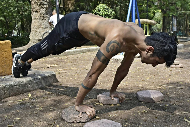 man doing h ups on a boulder on a park