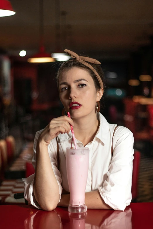 a girl wearing a pony tail while holding a drink