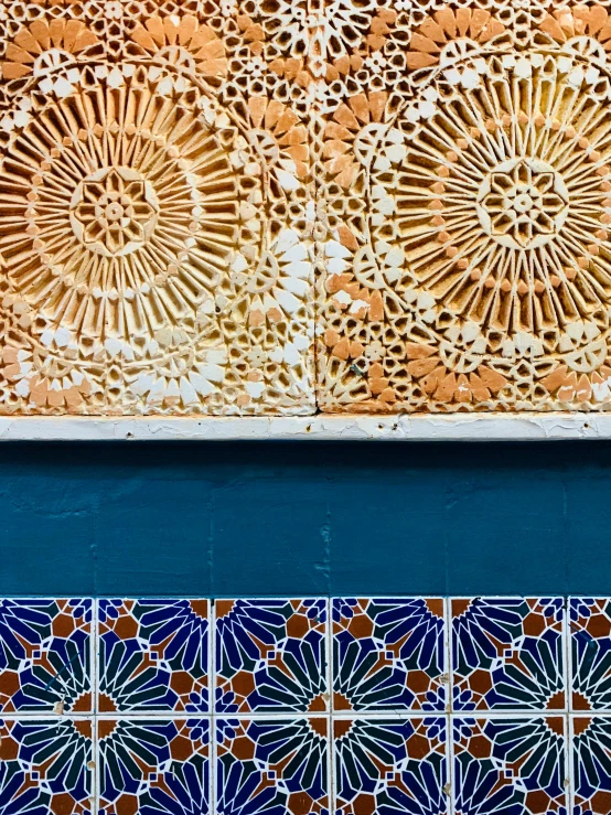 different colored tile designs in front of a blue wall