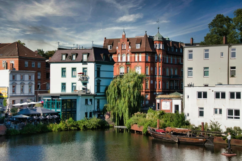 many boats are docked on the bank of a river in a city