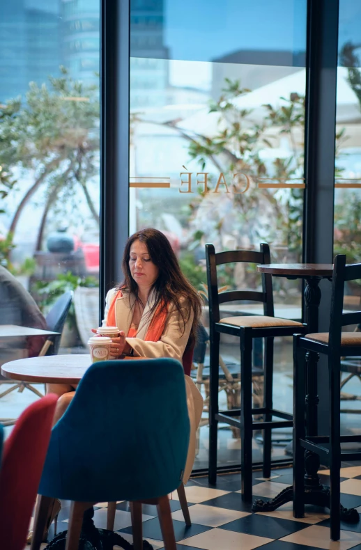 the woman is sitting at a table in front of her glass windows