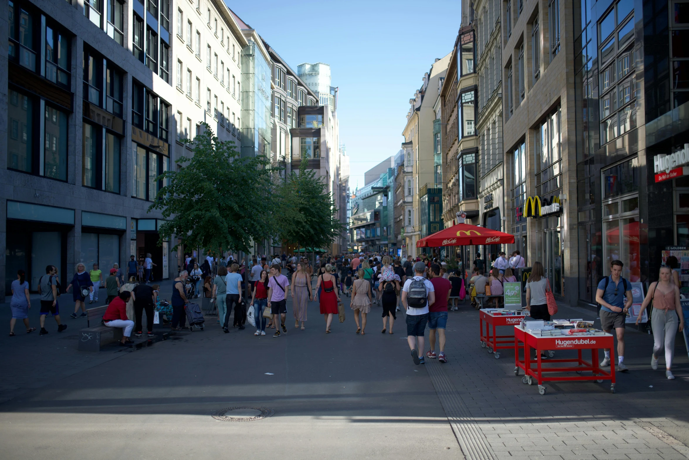 many people walking along the street with buildings on both sides