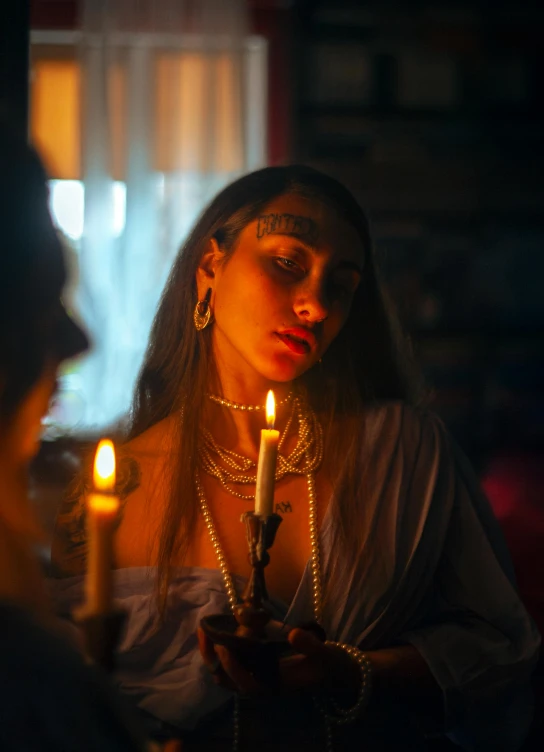 two women standing by one another with candles in the background