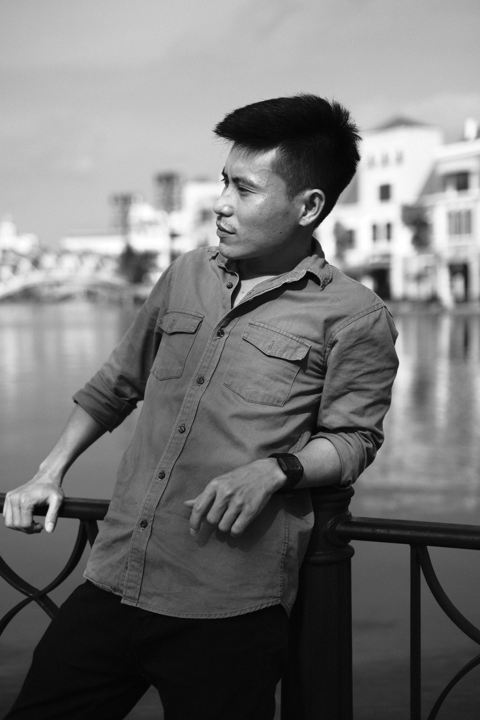 man standing next to water on railing in urban area