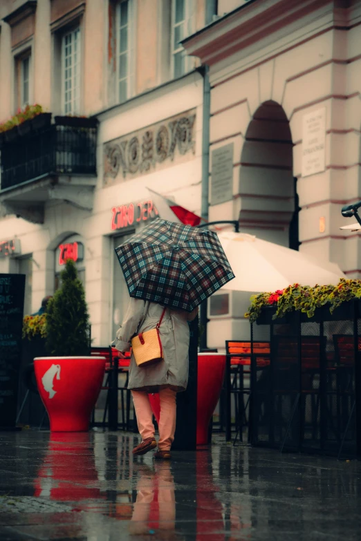 a person walking on the wet sidewalk with an umbrella