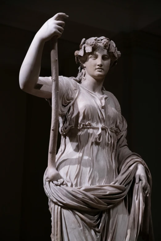 a statue is sitting holding an arrow and a staff