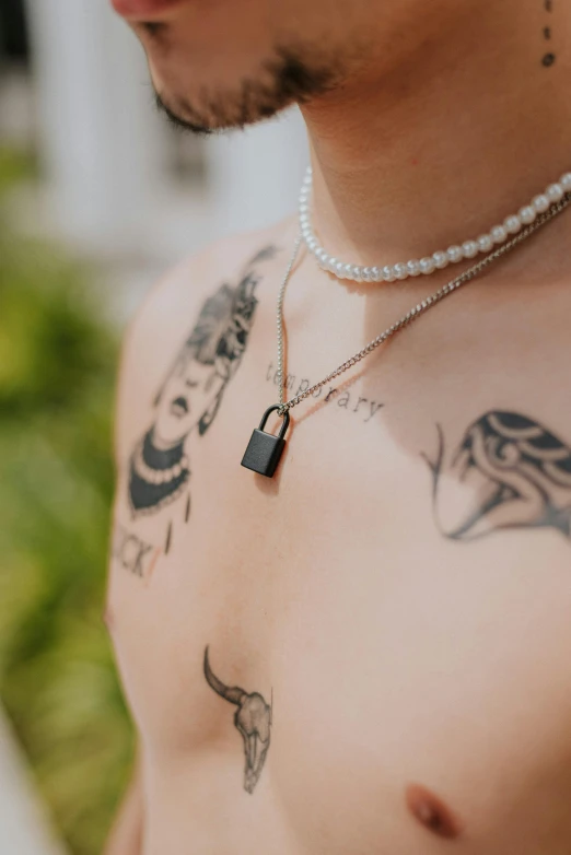 man with tattoos on his chest wearing a necklace and a necklace chain