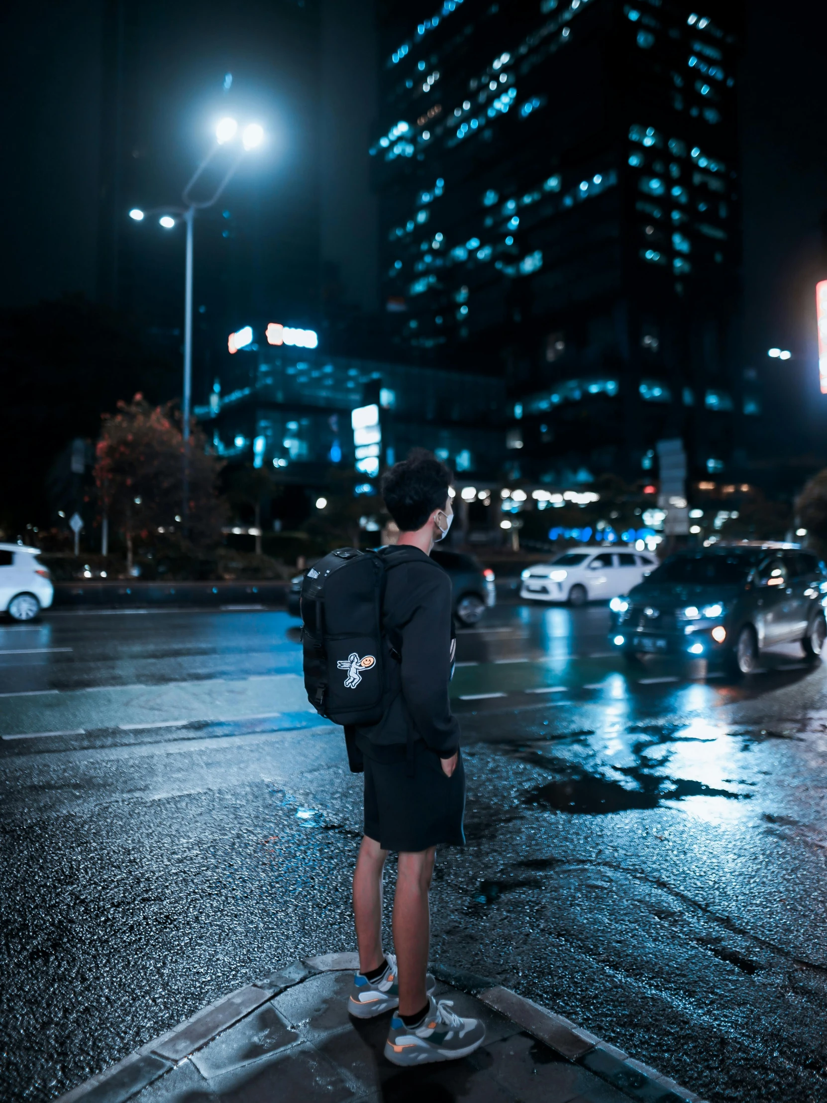 a man is standing in the middle of a wet street with an umbrella over his head