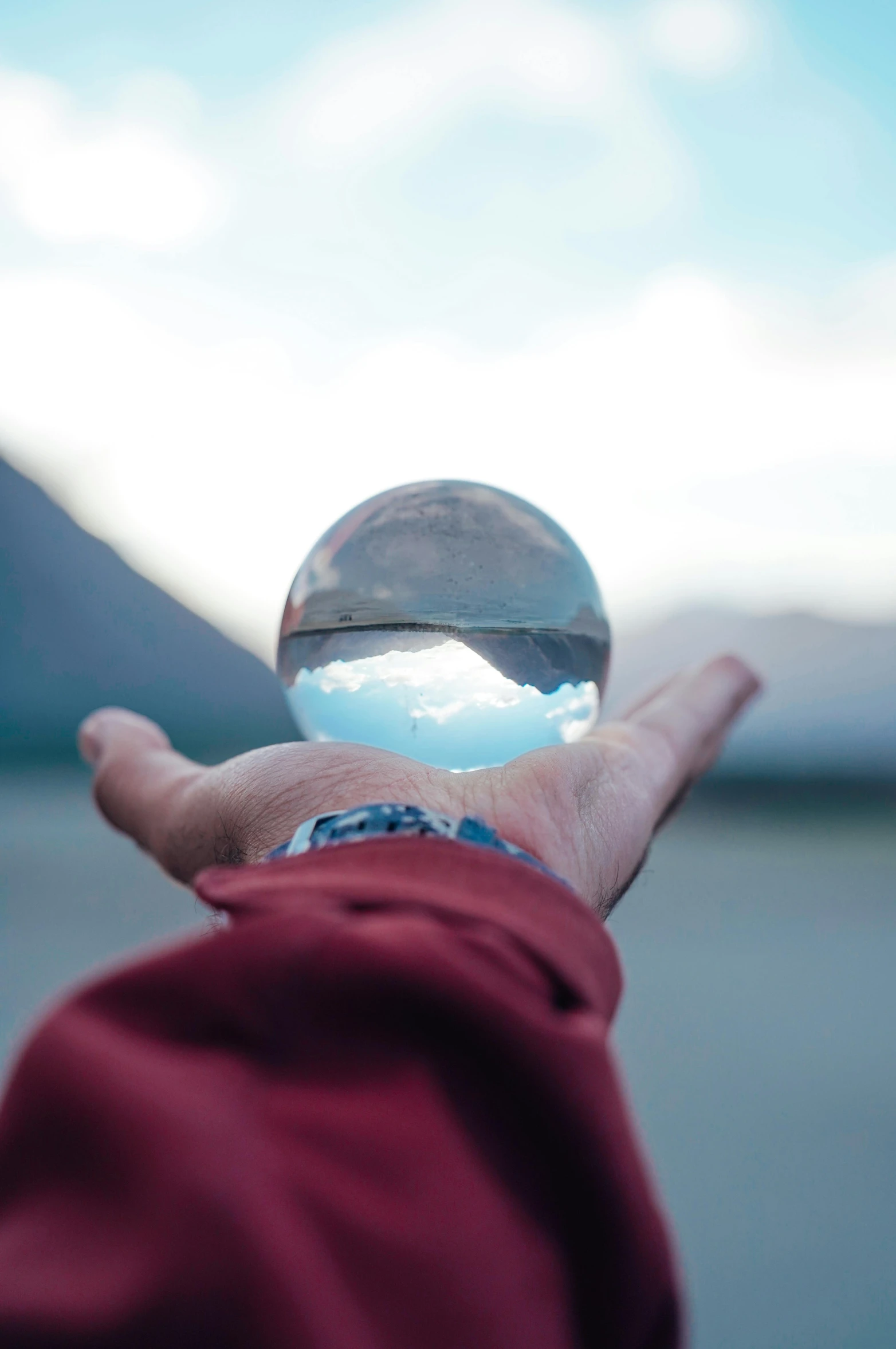 a person holds their hands out and is reflecting the blue sky and white clouds