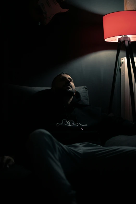 man lying on bed under a red lamp in dark room