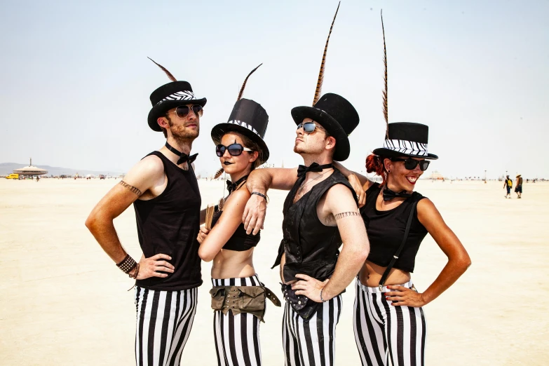 four men in striped pants and hats at the beach