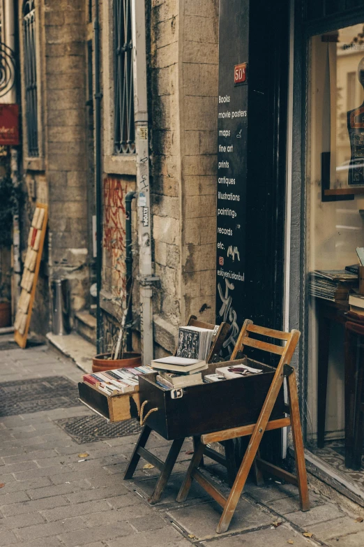 a small wooden chair is next to an old newspaper rack