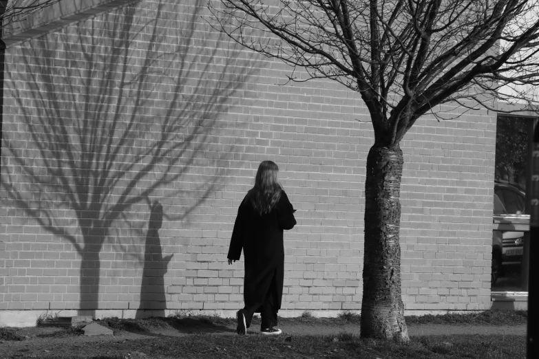 a woman in a long dress standing next to a tree