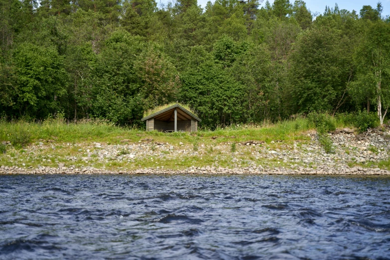 a hut nestled on a lake surrounded by trees