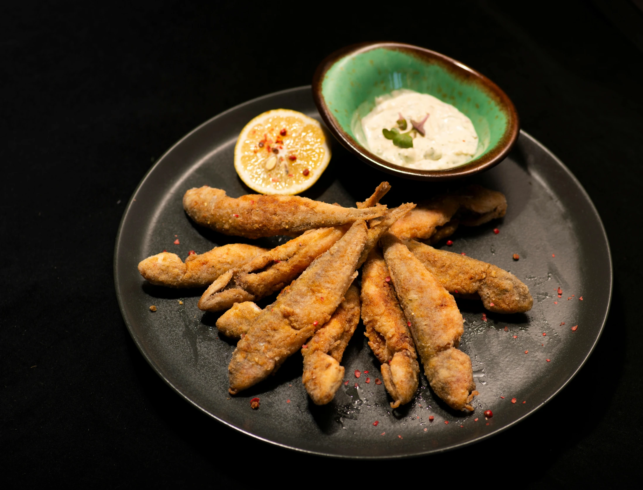 a plate with chicken sticks, sauce, and fruit on a table