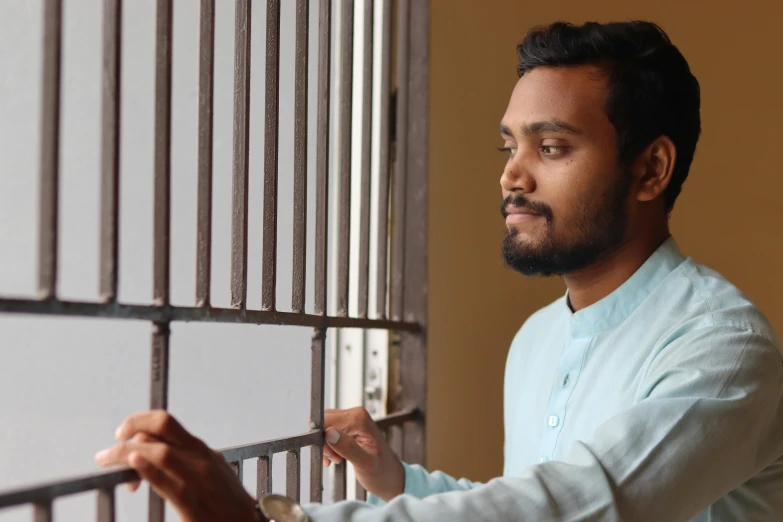 a man standing behind  bars as he looks into a mirror