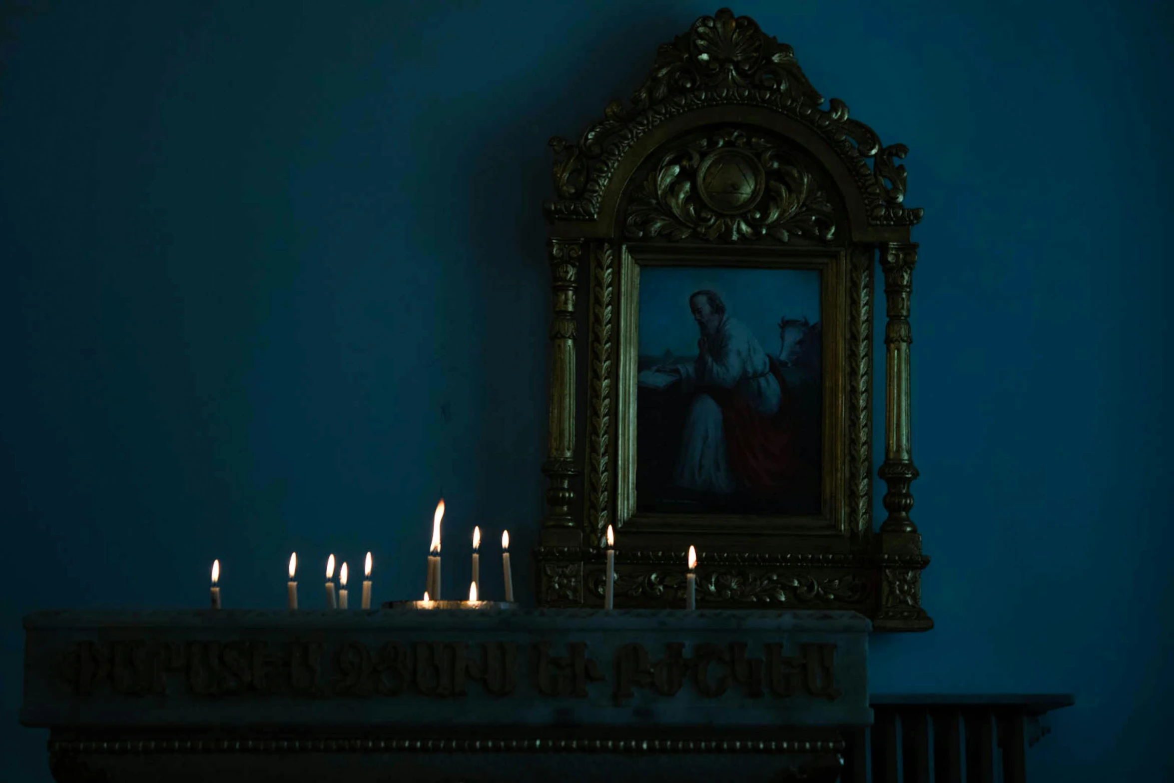 lit candles in front of a painted painting on a fireplace mantel