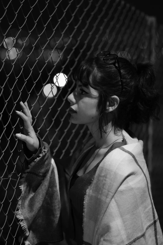 a woman holding up a ball behind a mesh net