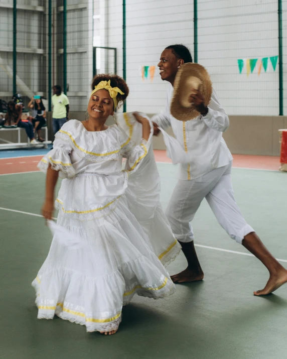 two people wearing dresses standing on a basketball court