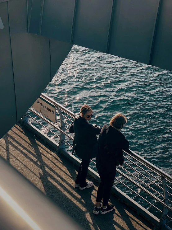 two people standing on the edge of a pier over looking the water
