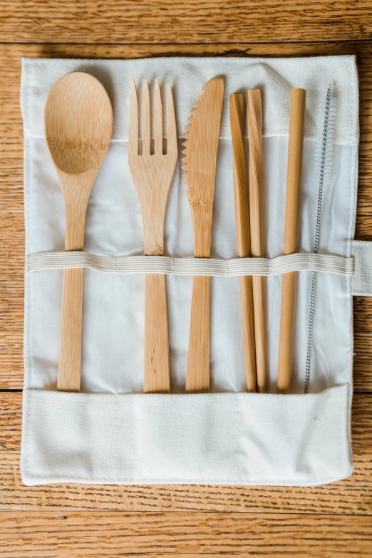 a wooden spoon, fork, knife and some utensils in a napkin