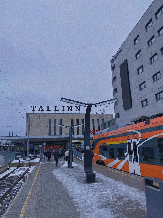 an orange train is at a station in the snow