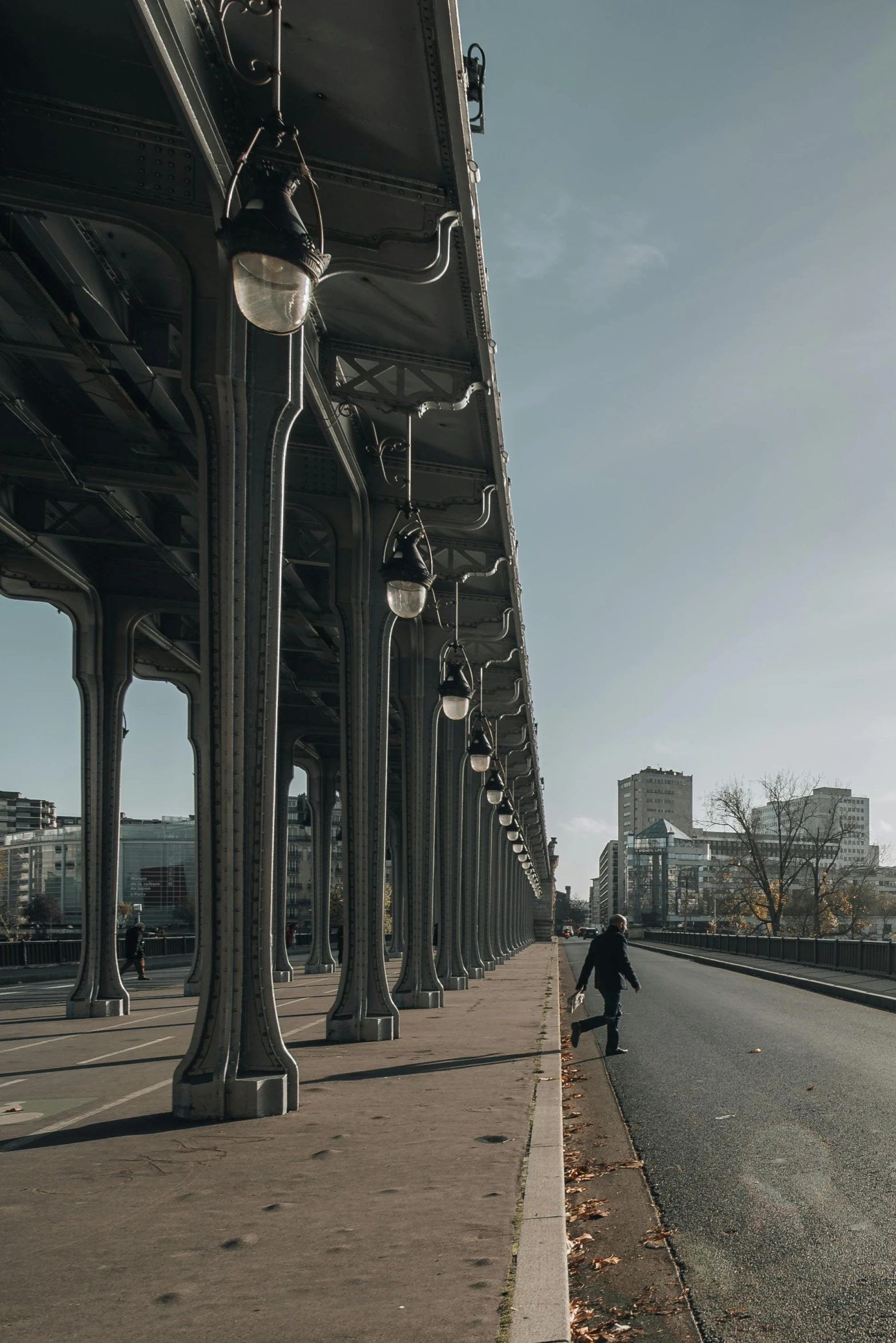 the person is standing under the bridge on his bicycle