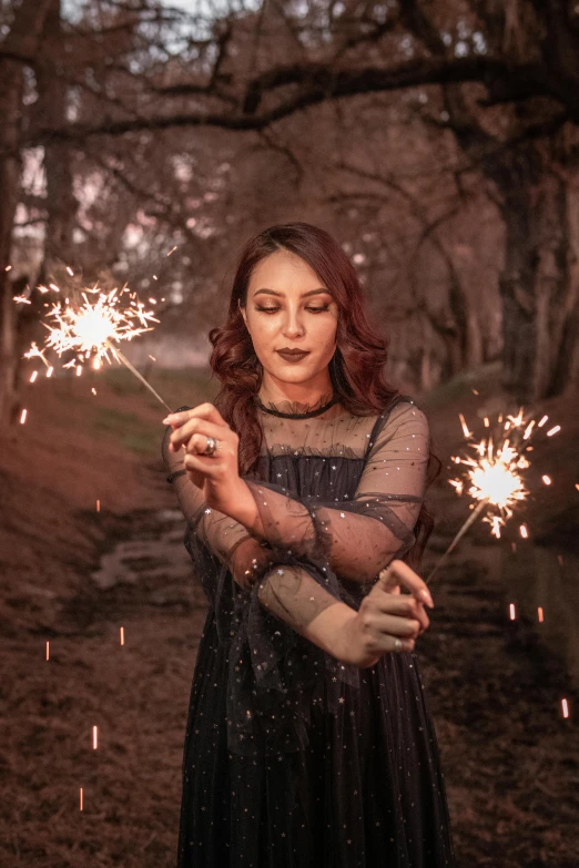 a woman holding sparklers in a park