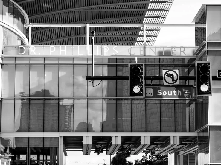 people are crossing a street by a building with glass walls