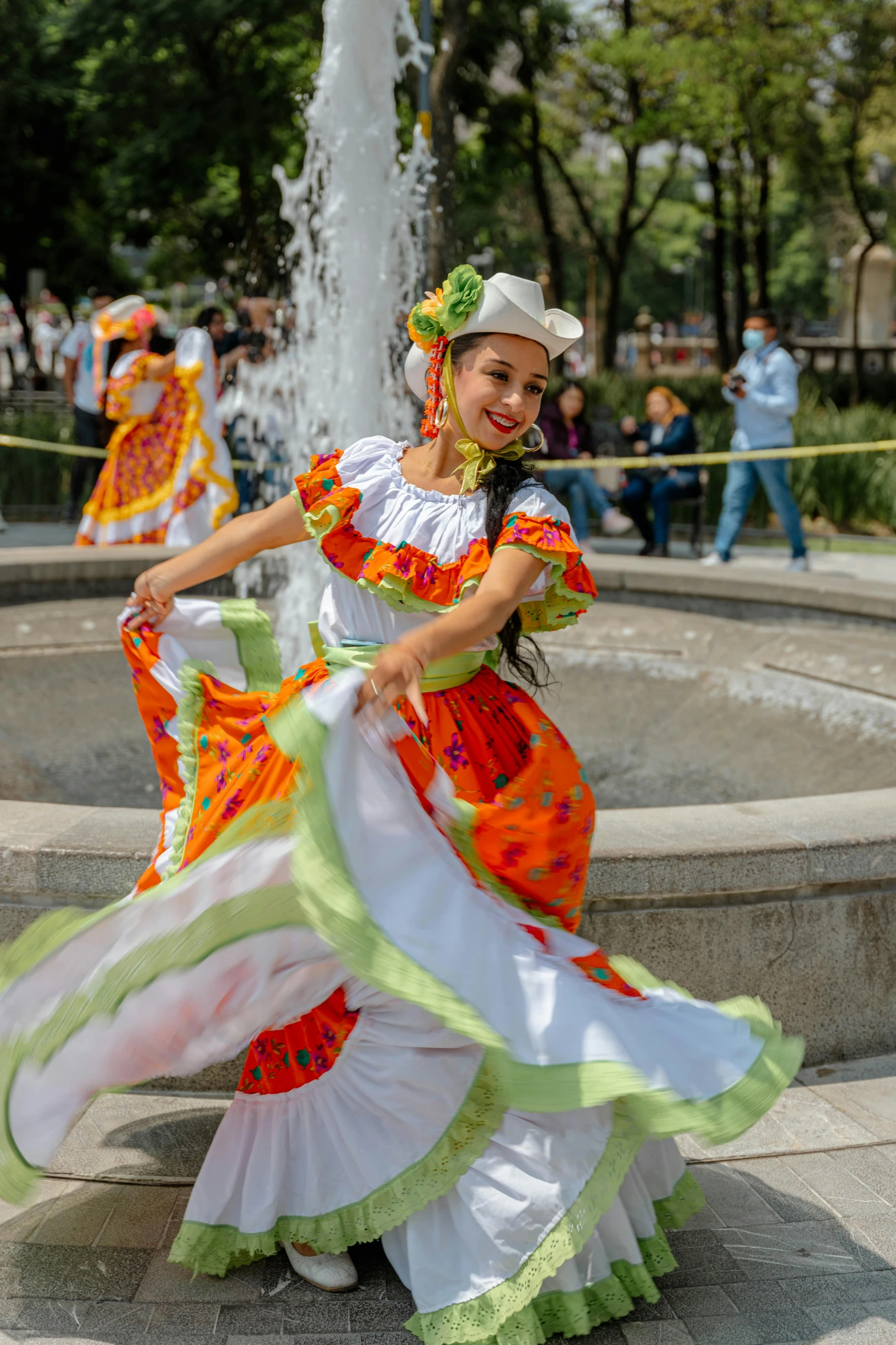 a woman dancing in colorful dresses around a fountain