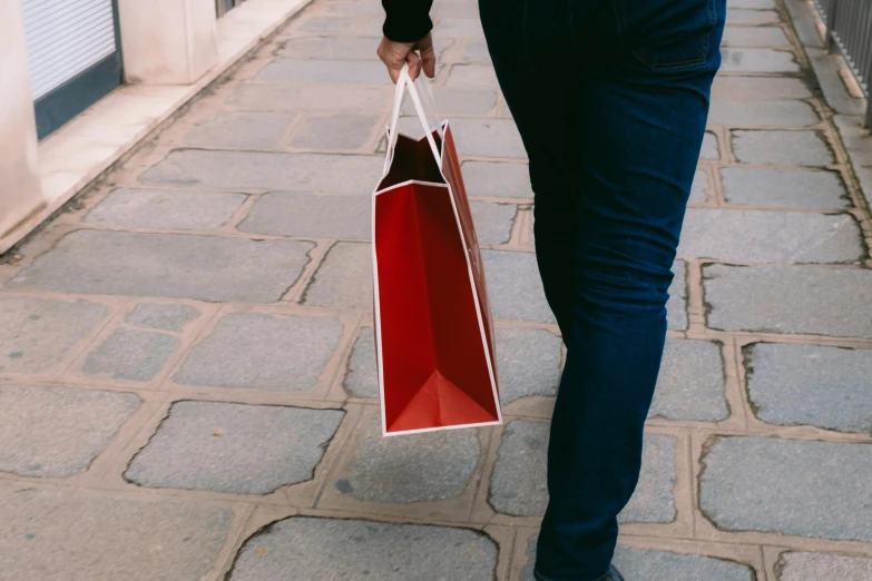 a man is carrying a shopping bag on a sidewalk