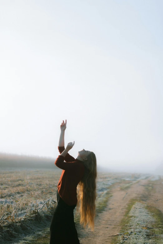 a woman standing on a road reaching for a sky line