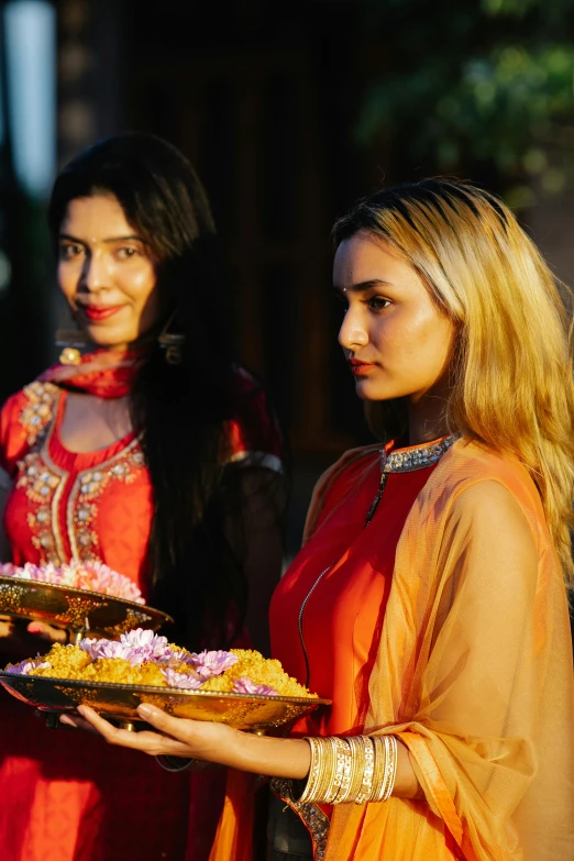 a couple of women holding onto a plate of food