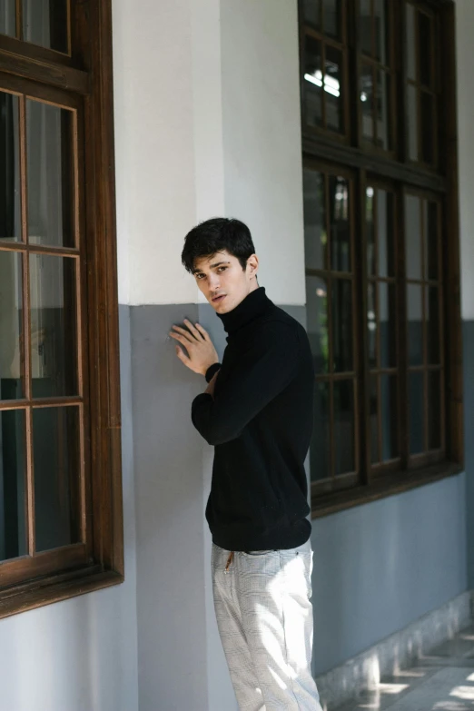 a young man leaning up against the side of a building