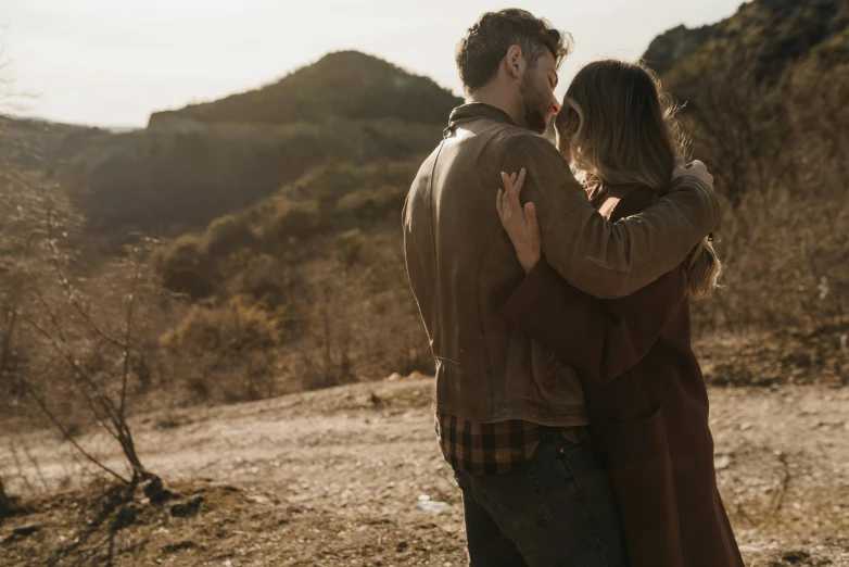 two people looking at each other and standing on top of a hill