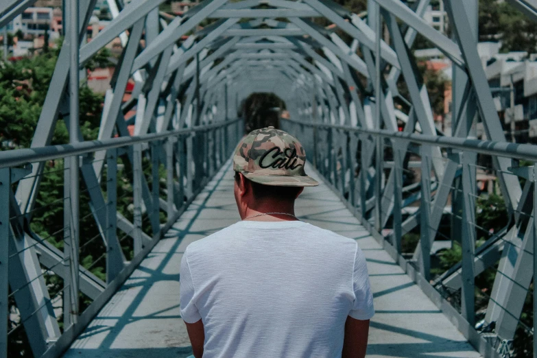 a man in a hat is standing on a bridge