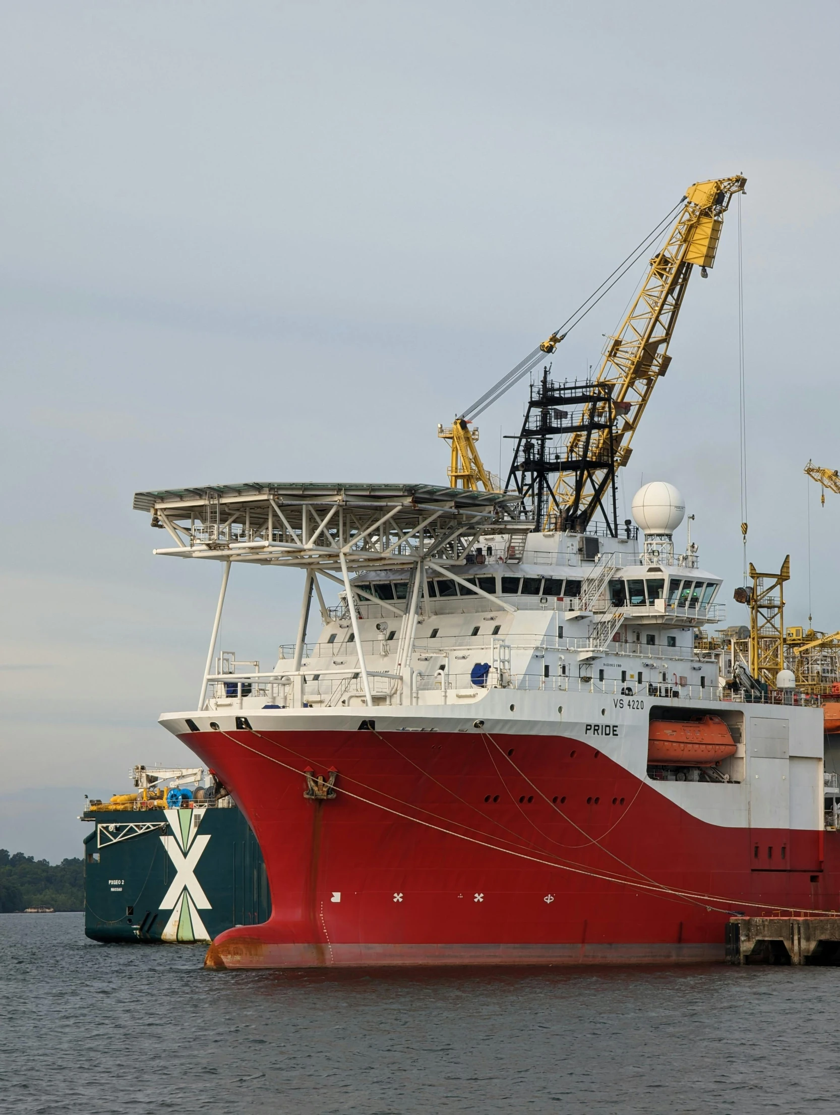 a large boat parked at the dock beside a crane