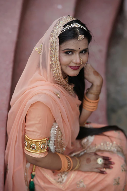 woman in indian attire sitting in a pink structure