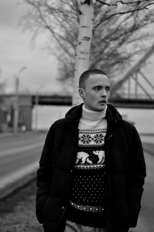 a young man in black jacket next to a tree