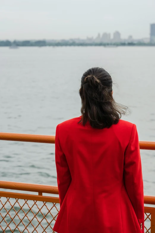 a woman wearing a red suit stands near water