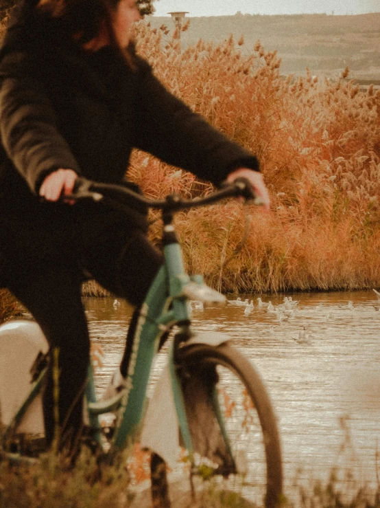 a lady riding her bicycle by a river