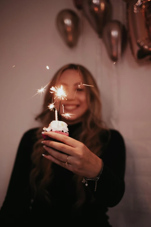 a girl holding a birthday cake with sparklers on top
