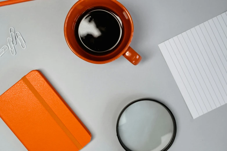 the cup of coffee is on a desk next to an open notebook